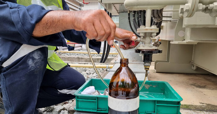 Technician extracts oil from a power transformer to perform a manual Dissolved Gas Analysis (DGA)