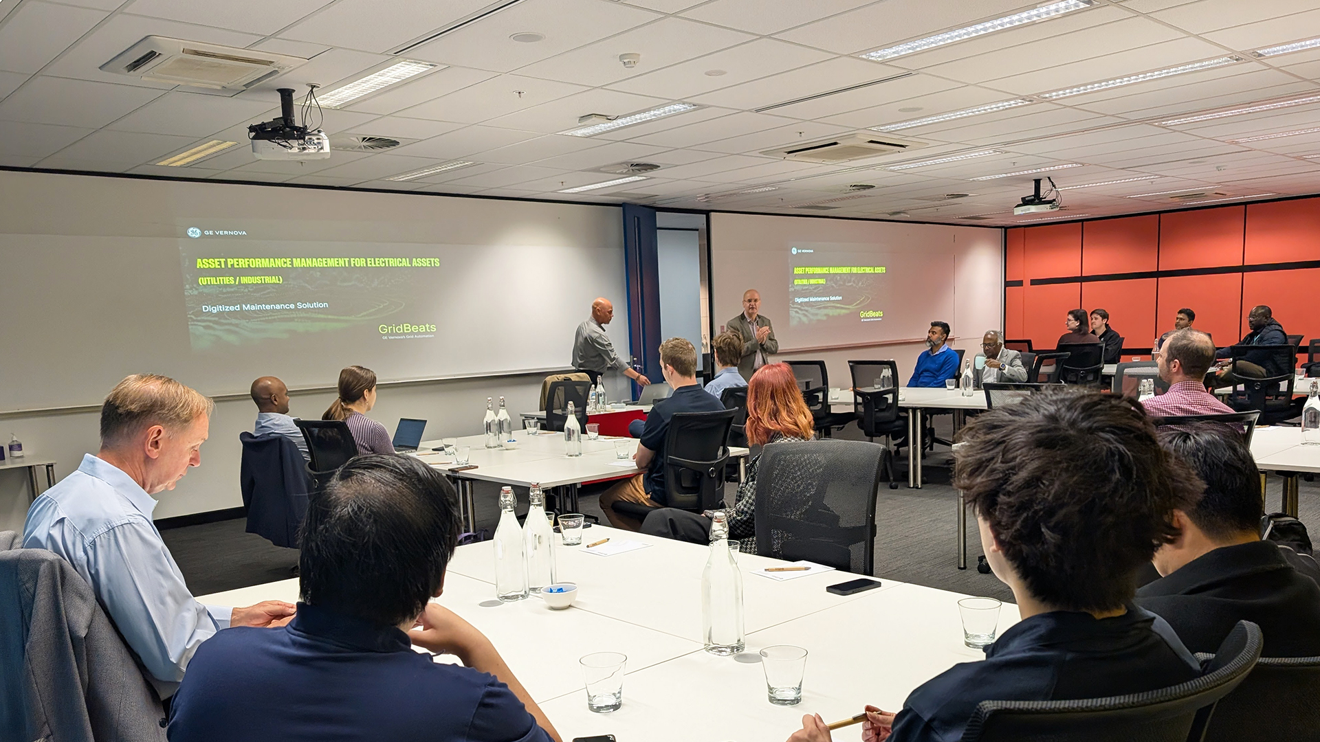 People attending a presentation on "Asset Performance Management for Electrical Assets" in a modern, well-lit conference room.