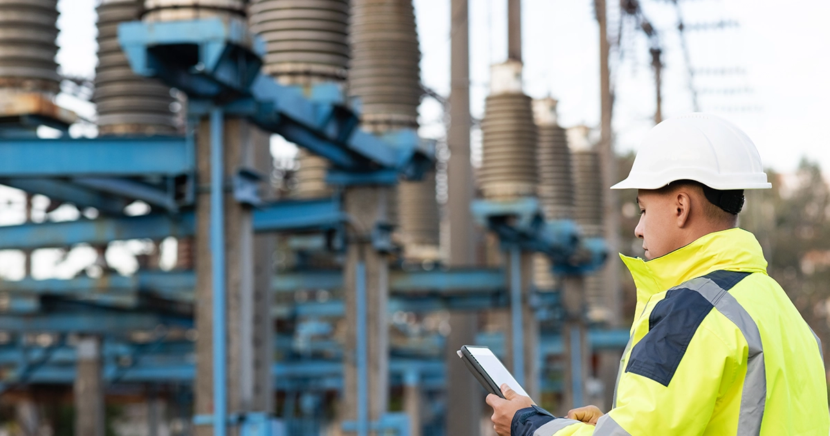 Utilities personnel consult a tablet to perform condition-based monitoring for a transformer using the IM500 sensor from Systems with Intelligence